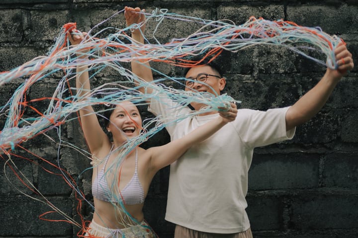 两人在彩色丝线间开心大笑