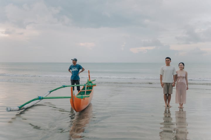 两人在浅水中走过小船
