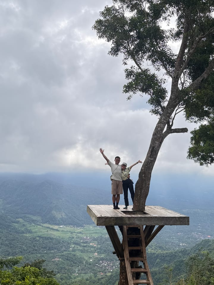 两人站在山景前的独树平台上