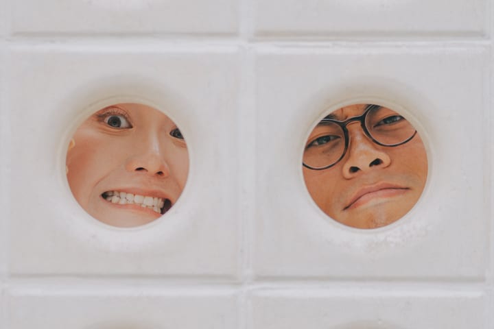 两人从圆形窗格中探出笑脸
