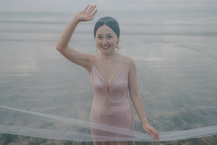 一人在海边薄纱后微笑挥手